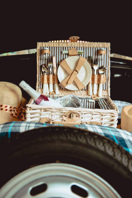 Подарункова сумка з пляшкою шампанського і дорогими столовими приборами біля автомобільного колеса в багажнику — стокове фото