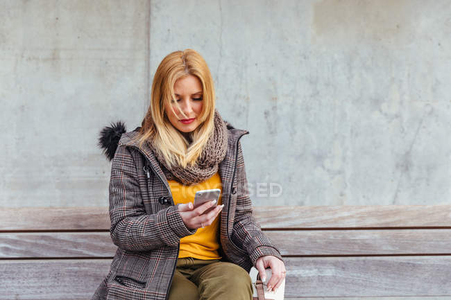 Ritratto di donna bionda che usa il suo cellulare per strada — Foto stock