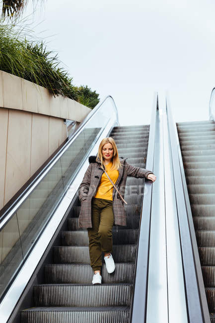 Блондинка спускається на ескалатори в торговому центрі. — стокове фото