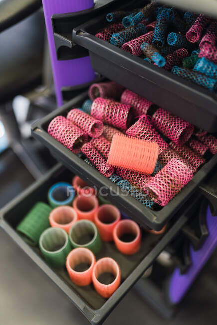 From above collections of different hair rollers placed on trays in shelves in hairdressing salon — Stock Photo