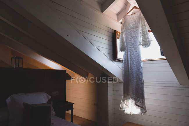 Leichtes Kleid trocknet bei geöffnetem Fenster in dunklem Dachboden des Hauses — Stockfoto