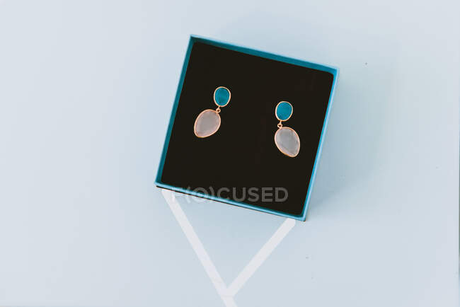 Dall'alto meravigliosi orecchini costosi in scatola blu su sfondo grigio — Foto stock