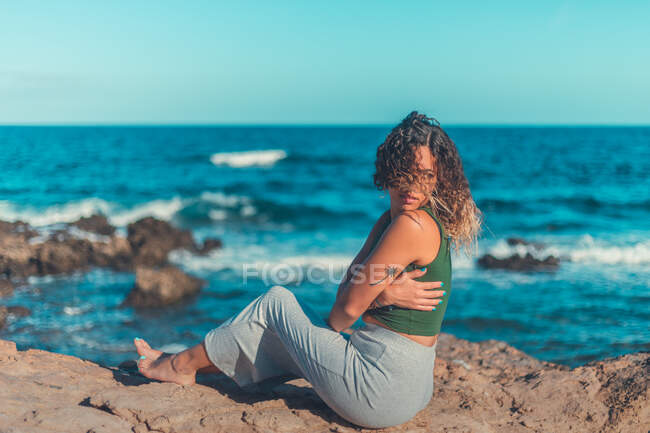 Стильна жінка, що сидить біля моря — стокове фото