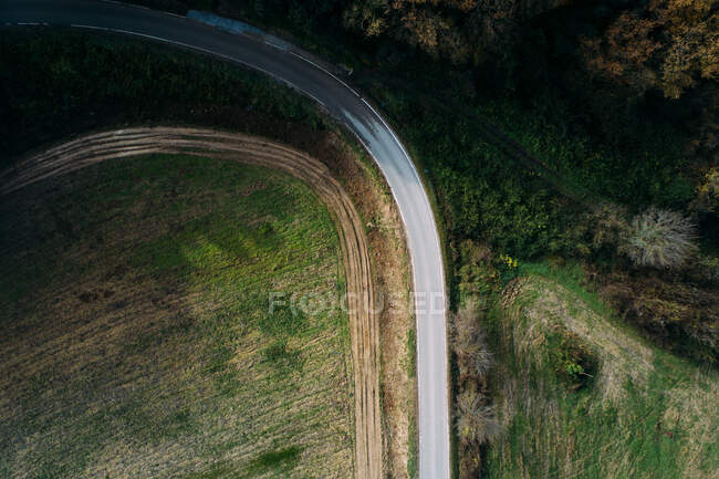 Bela vista drone de van moderna montando na estrada de asfalto perto do campo verde no dia ensolarado no campo — Fotografia de Stock
