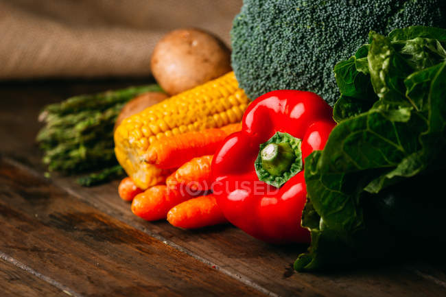 Assortiment de légumes crus frais en tas sur table en bois — Photo de stock