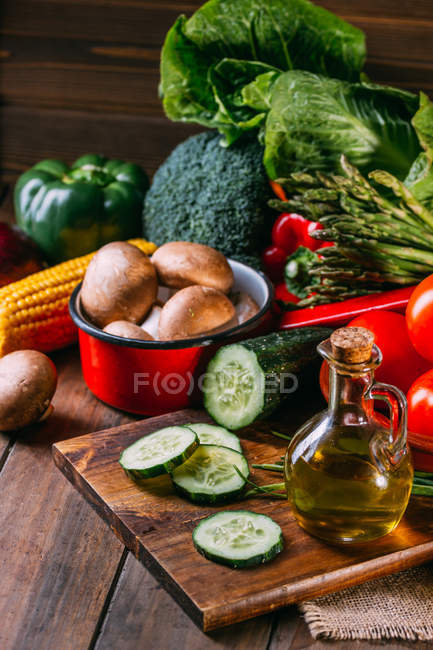 Assortment of fresh raw vegetables and utensils on wooden kitchen table — Stock Photo