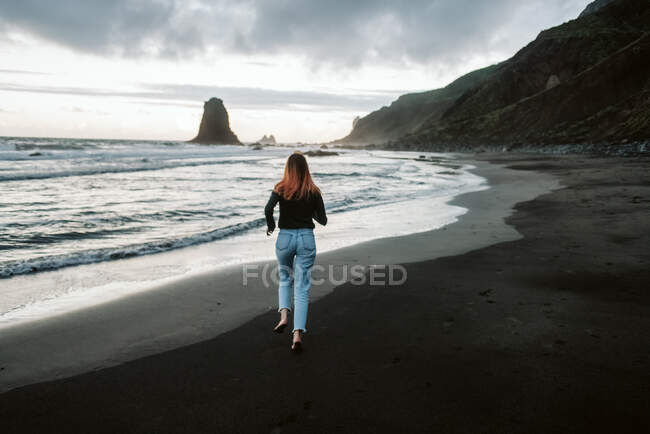 Barefoot female running near waving sea — Stock Photo