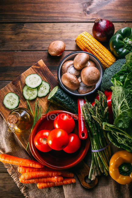 Assortment of fresh raw vegetables and utensils on wooden kitchen table — Stock Photo