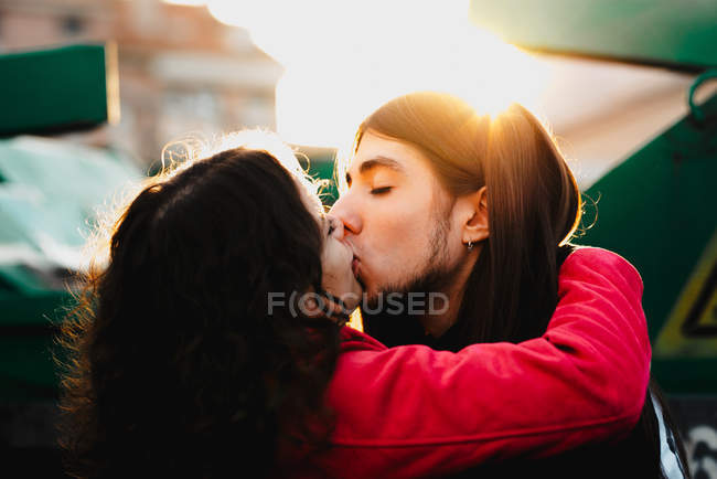 Homme aux cheveux longs embrassant et embrassant femme près du train — Photo de stock