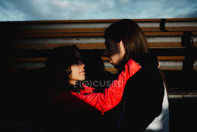 Довгошерстий чоловік обіймає і цілує жінку біля поїзда — стокове фото