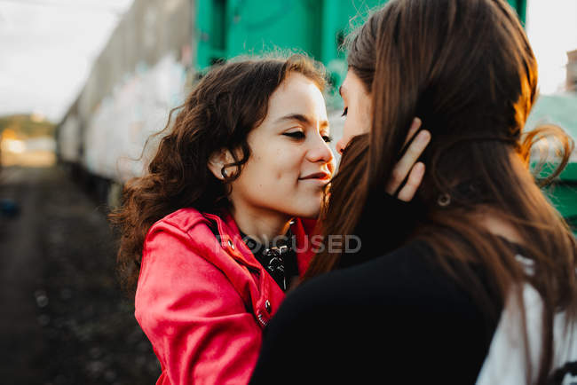 Homme aux cheveux longs embrassant et embrassant femme près du train — Photo de stock