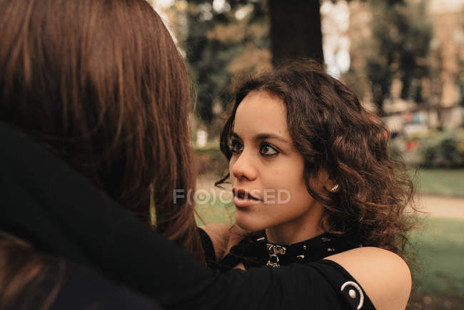 Long haired man hugging and kissing woman near tree — Stock Photo