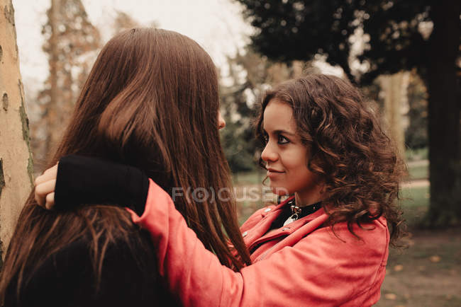 Long haired man hugging and kissing woman near tree — Stock Photo