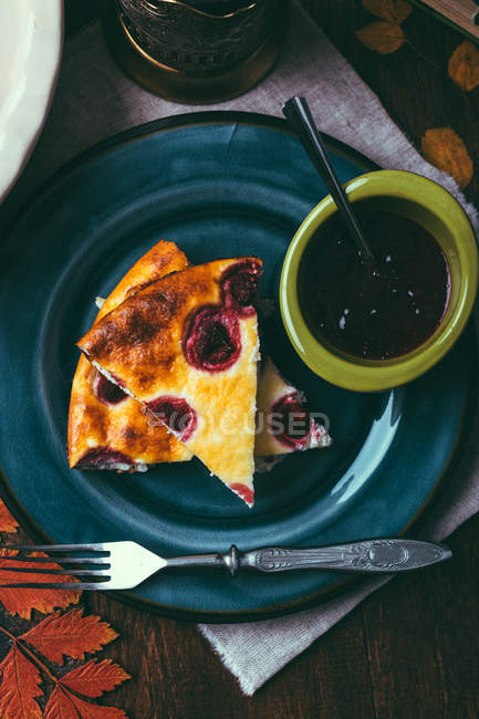 From above ceramic plate with pieces of delicious pie and bowl of sweet jam placed on table. — Stock Photo