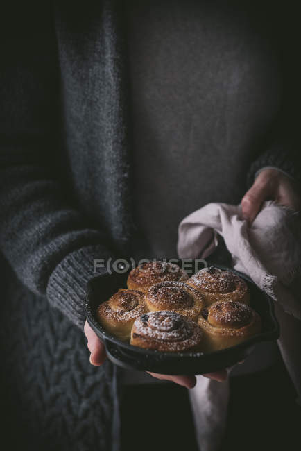 Cropped of woman holding cinnamon rolls in small pan. — Stock Photo