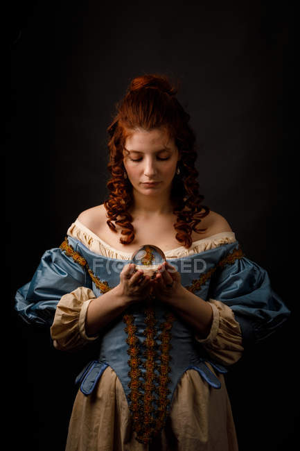 Barockfrau blickt herab, während sie magische Glaskugel in der Hand hält. — Stockfoto