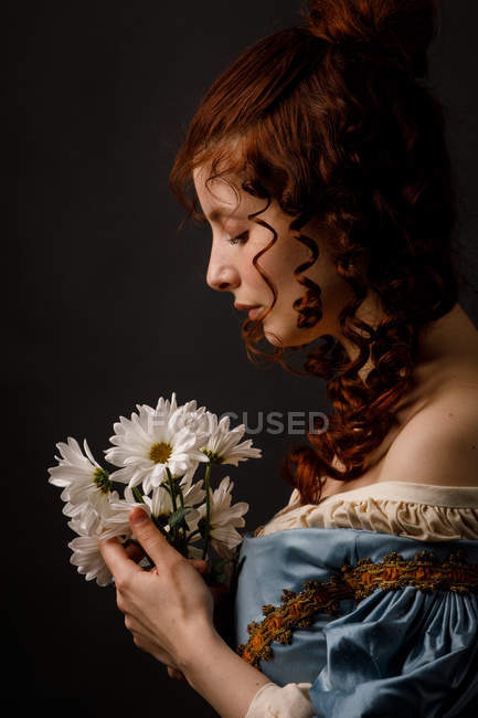 Beautiful woman in medieval clothing holding bunch of flowers. — Stock Photo