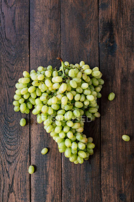 Ramo de uvas verdes maduras sobre mesa de madera . - foto de stock