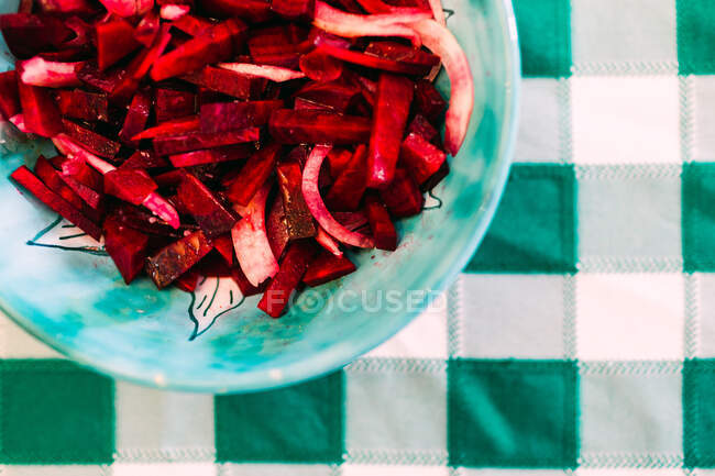 Closeup bowl with fresh beetroot salad placed on table with checkered tablecloth — Stock Photo