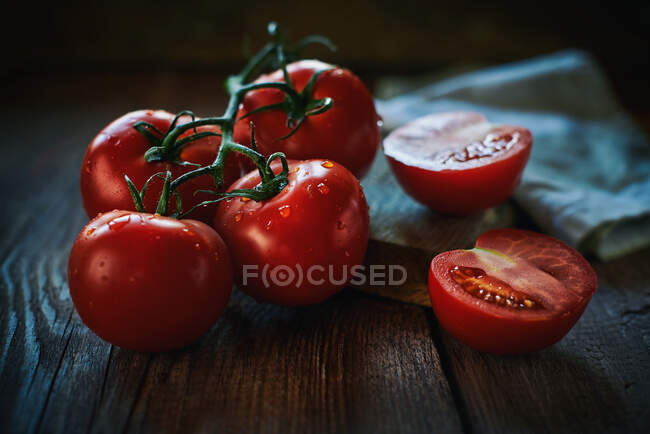 Closeup bunch of wet ripe tomatoes placed near napkin on lumber tabletop — Stock Photo