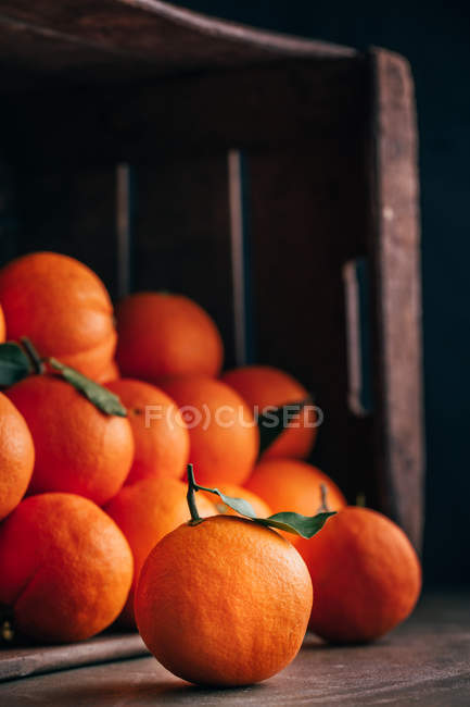 Oranges fraîches dans une vieille boîte en bois renversée — Photo de stock