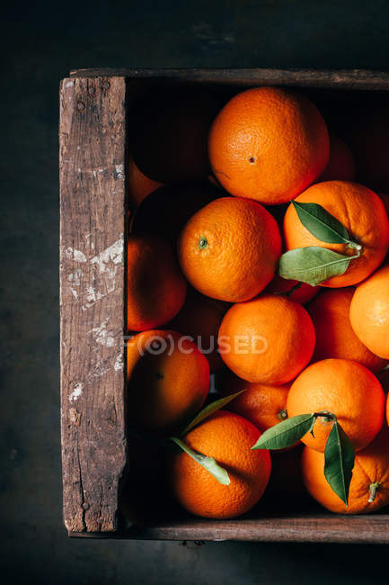 Свіжі апельсини в старій дерев'яній коробці на темному фоні — стокове фото