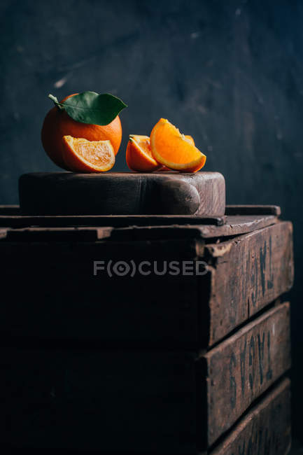 Naranjas frescas enteras y cortadas sobre fondo de madera oscura - foto de stock