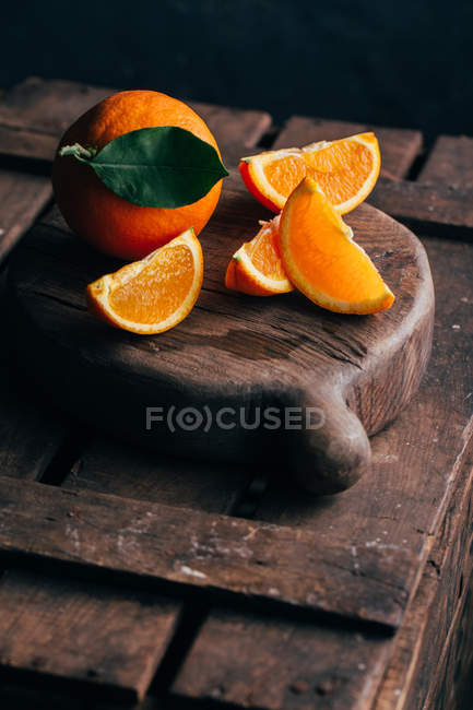 Fresh whole and cut oranges on dark wooden background — Stock Photo