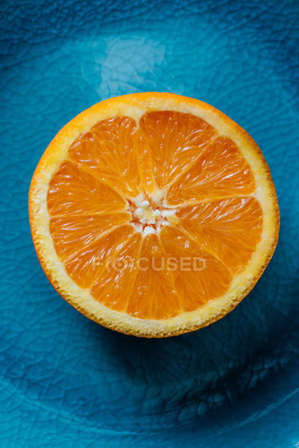 Крупный план свежей оранжевой половины на голубой тарелке — стоковое фото