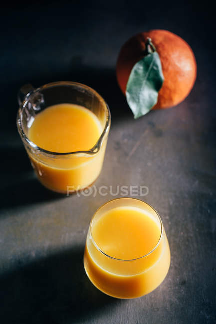 Sumo de laranja em óculos no fundo escuro — Fotografia de Stock
