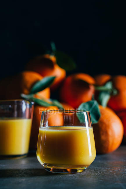 Succo d'arancia in bicchieri su sfondo scuro — Foto stock