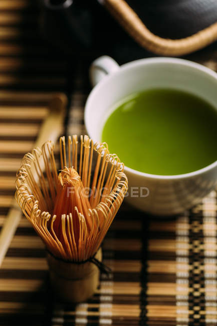 Gros plan de la tasse avec thé matcha vert frais et outil de préparation du fouet de bambou sur la table . — Photo de stock