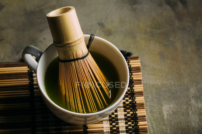 Primer plano de la preparación de té matcha con batidor de bambú . - foto de stock
