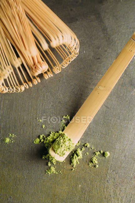 Close-up de pó de chá matcha verde em pequena colher e batedor de bambu . — Fotografia de Stock