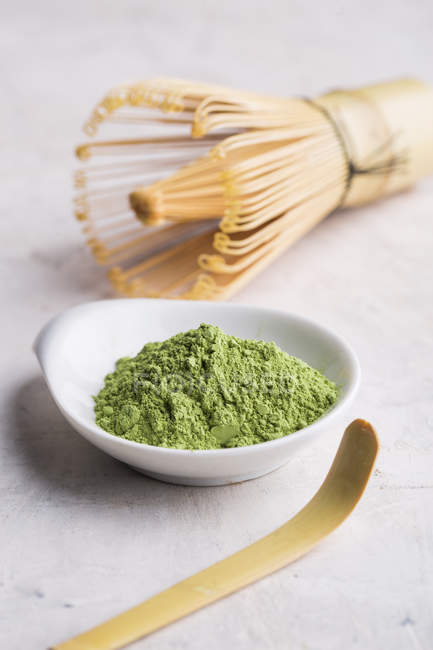 Pó de chá matcha verde e batedor de bambu com colher na mesa . — Fotografia de Stock