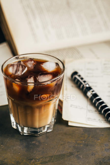 Café expresso frio em vidro no fundo escuro grunge com livro antigo — Fotografia de Stock