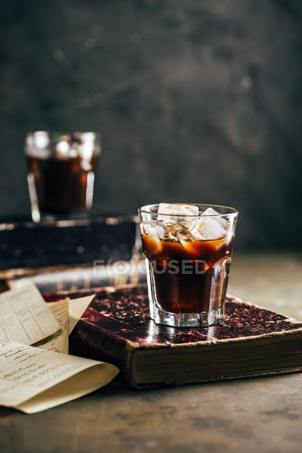 Café expresso frio em vidro no fundo escuro grunge com livro antigo — Fotografia de Stock