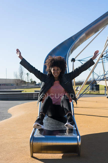 Жінка з афро волоссям стрибає на слайді з великою радістю — стокове фото