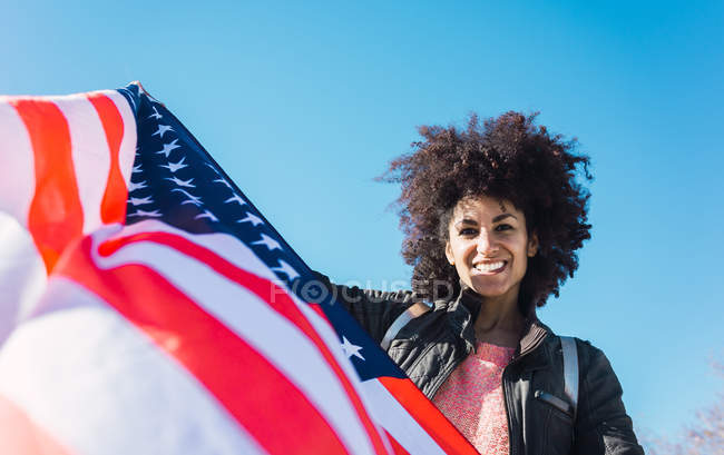Mulher negra com cabelo afro e uma bandeira americana comemorando o dia da independência dos EUA — Fotografia de Stock