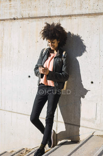 Черная женщина идет по улице со своим смартфоном — стоковое фото