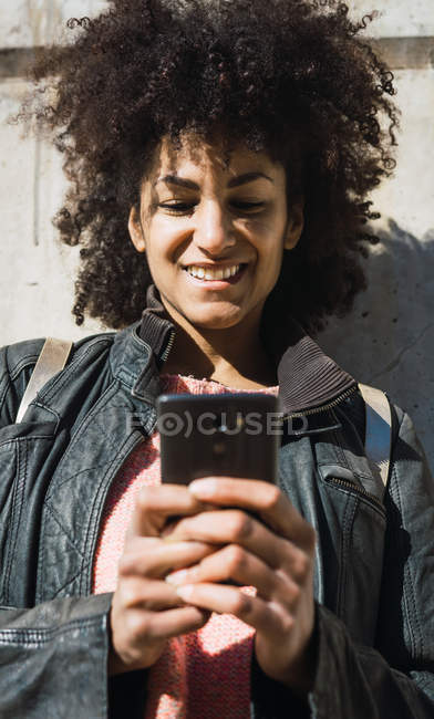 Portrait of black woman with afro hair leaning on a wall in the street — Stock Photo