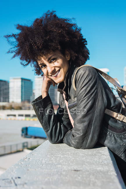 Retrato de mulher negra com cabelo afro apoiado em uma parede na rua — Fotografia de Stock