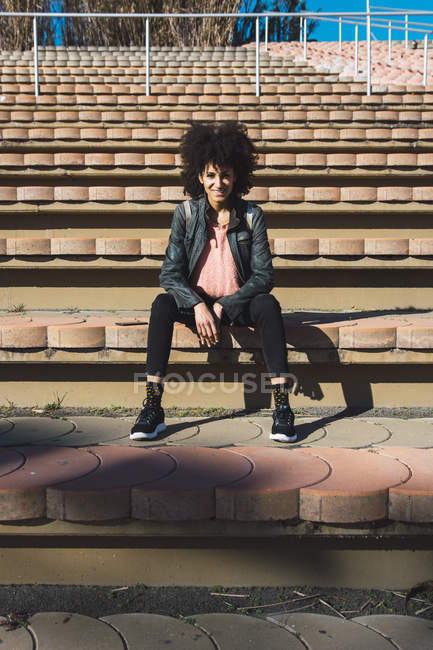 Schwarze Frau mit Afro-Haaren sitzt auf den Stufen eines Stadions — Stockfoto