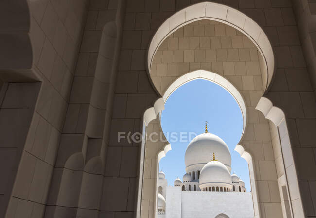 Vista do fantástico palácio branco através de incríveis arcos no dia ensolarado em Emirados Árabes Unidos — Fotografia de Stock
