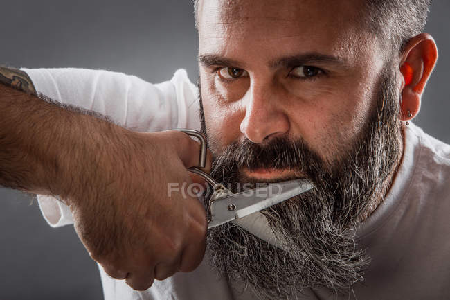 Экспрессивный парикмахер стрижет бороду — стоковое фото