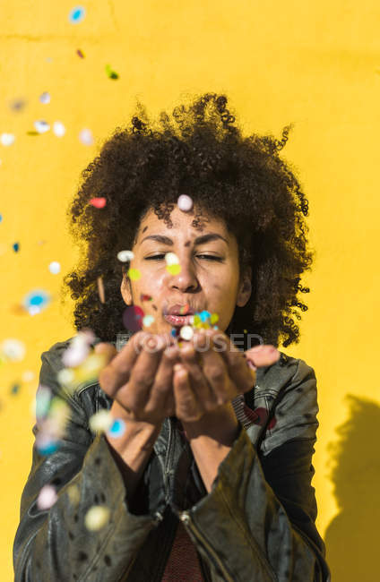 Femme noire avec des cheveux afro jetant confettis pour célébrer une journée très spéciale — Photo de stock