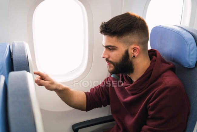 Ragazzo barbuto utilizzando smartphone in aereo — Foto stock