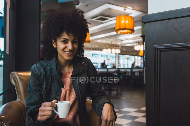 Schwarze Frau mit Afro-Haaren trinkt einen Kaffee in einem Café — Stockfoto