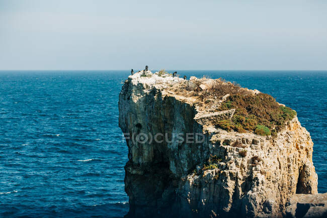 Majestic drone view of rough rocky cliff located in beautiful rippling sea on sunny day in nature — Stock Photo