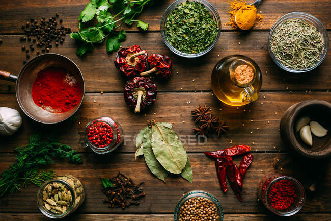 Assortiment d'épices et d'herbes et bouteille d'huile placée sur une table en bois — Photo de stock